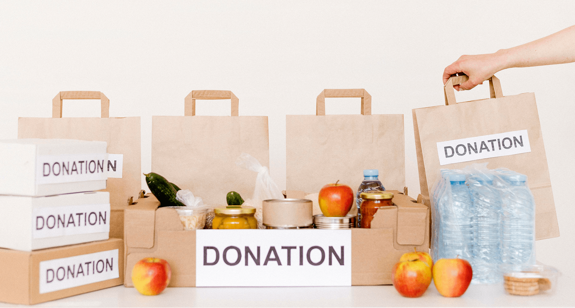 Boxes and bags labeled donation containing food items like apples, cucumbers, jars, canned goods, and bottled water.