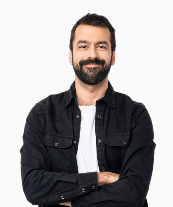 Smiling man with dark hair and beard wearing a black button-up shirt over a white t-shirt, arms crossed.