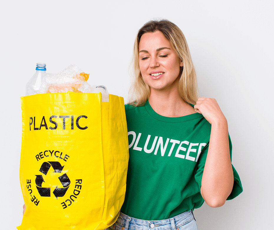 Woman wearing a green volunteer shirt holding a yellow recycling bag filled with plastic waste.