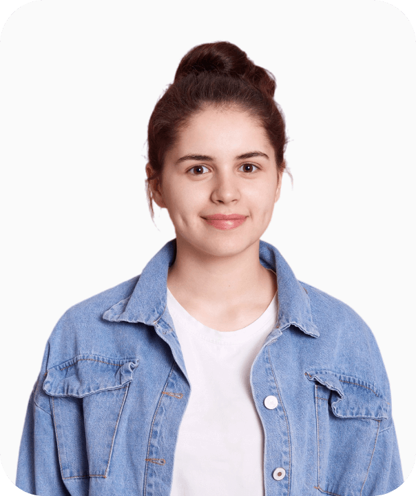 Smiling young man with short curly hair wearing a yellow shirt with rolled-up sleeves and a tattoo on his forearm, standing with arms crossed.