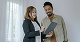 Smiling man and woman standing and looking at a document together indoors.